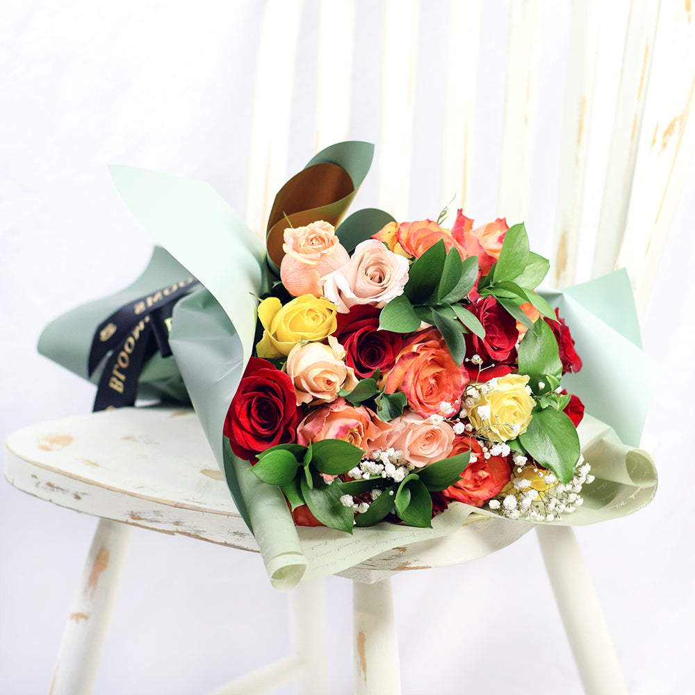 Bouquet with red, orange and yellow roses. Baby's breath and ruscus