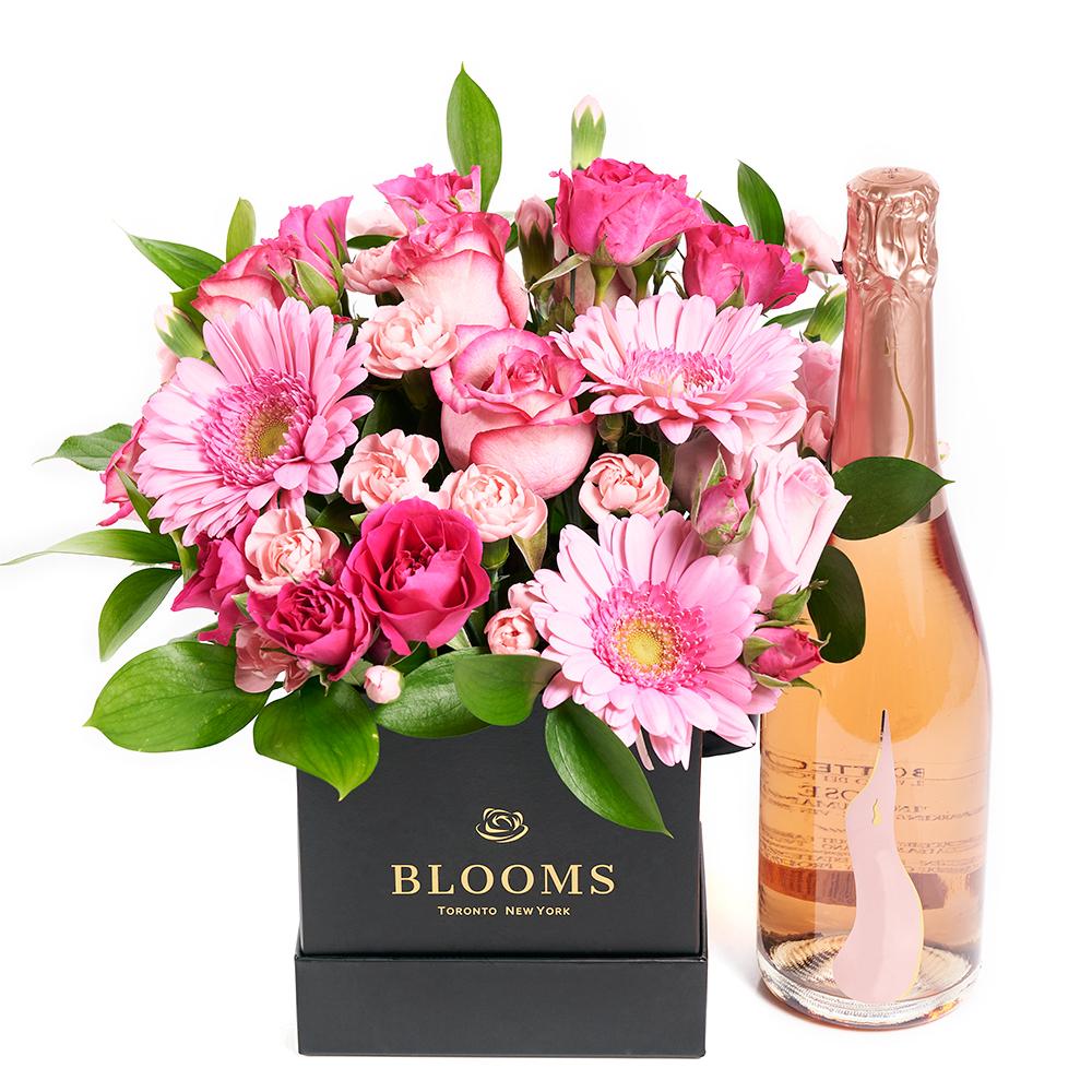 Boundless Cheer Flowers &amp; Champagne Gift, pink roses, gerbera, spray roses, mini carnations, and greens in a square black designer hat box, bottle of Sparkling Wine, Mixed Floral Gifts from Blooms New Jersey - Same Day New Jersey Delivery.